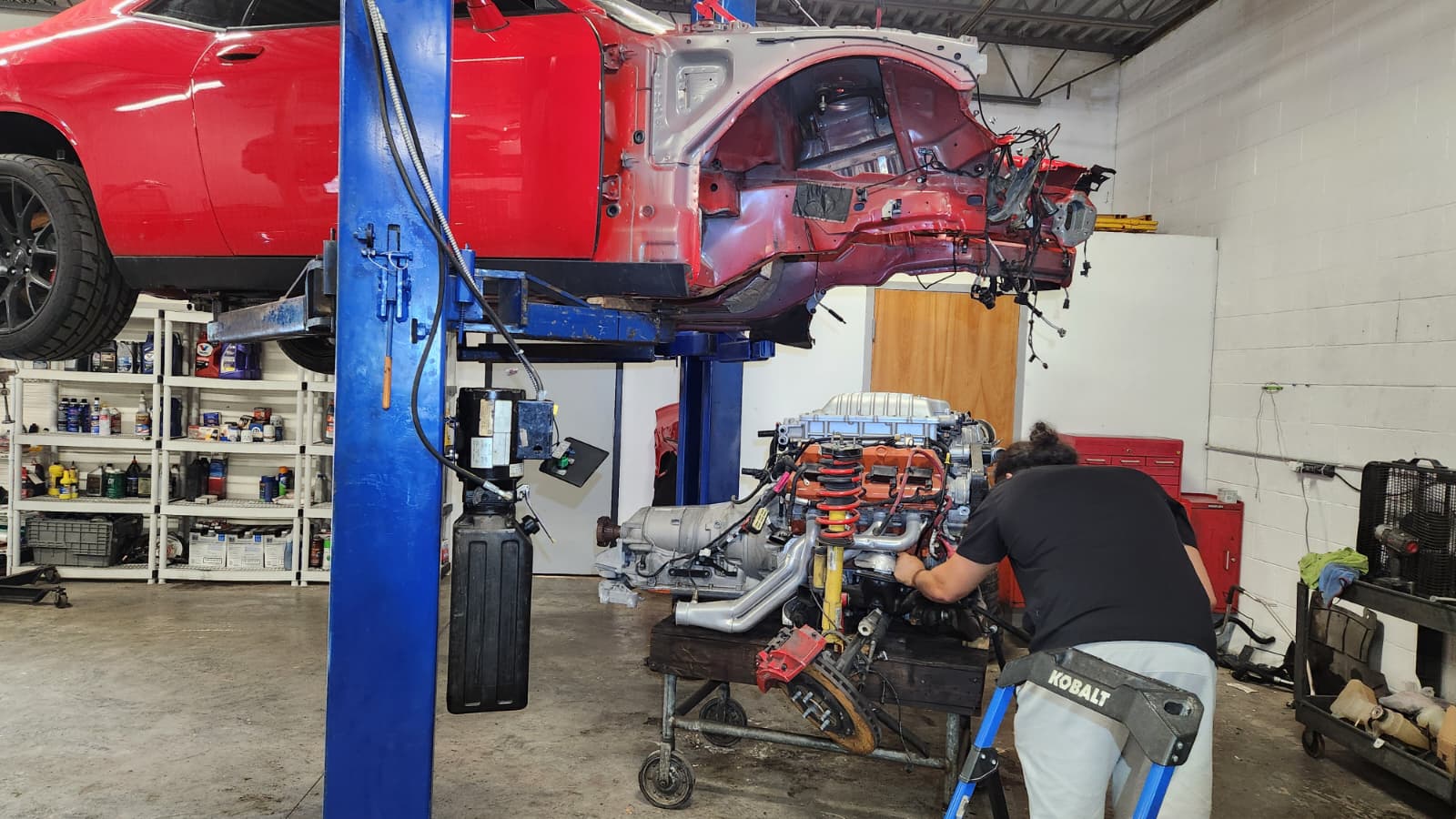 Technician performing engine rebuild on lifted car